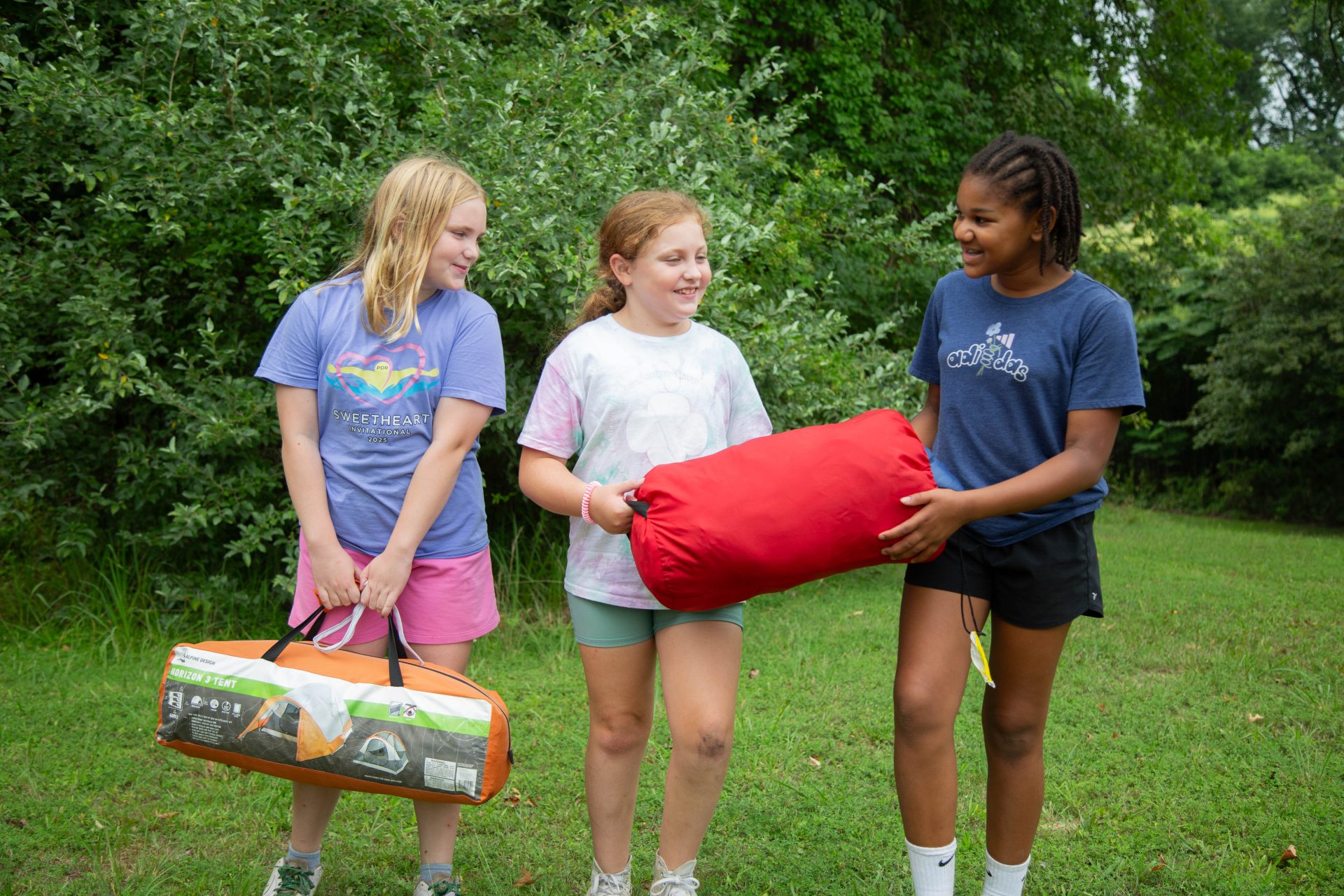 Three Girl Scouts with a camping tent kit