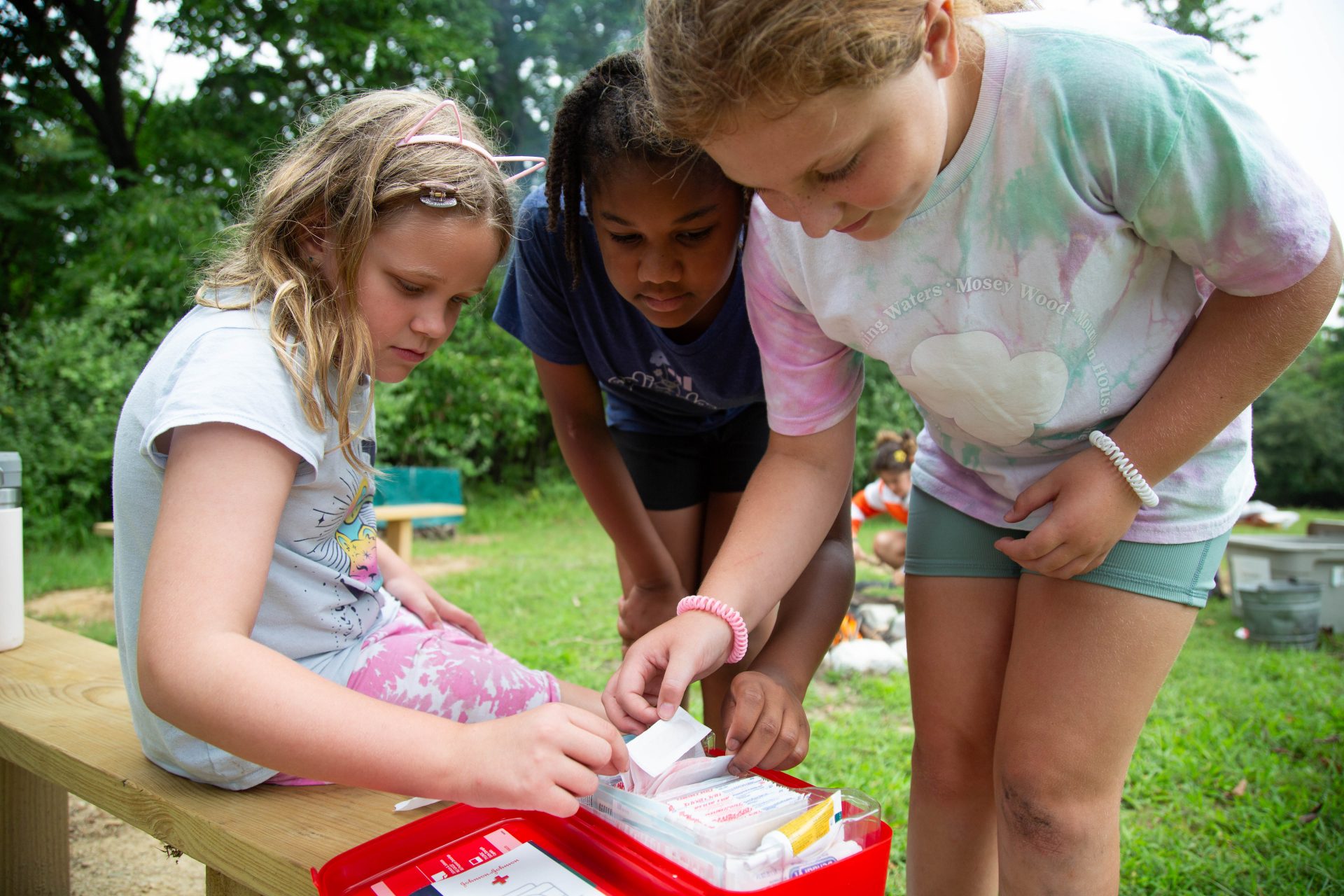 Three Girl Scouts looking through a first aid kit